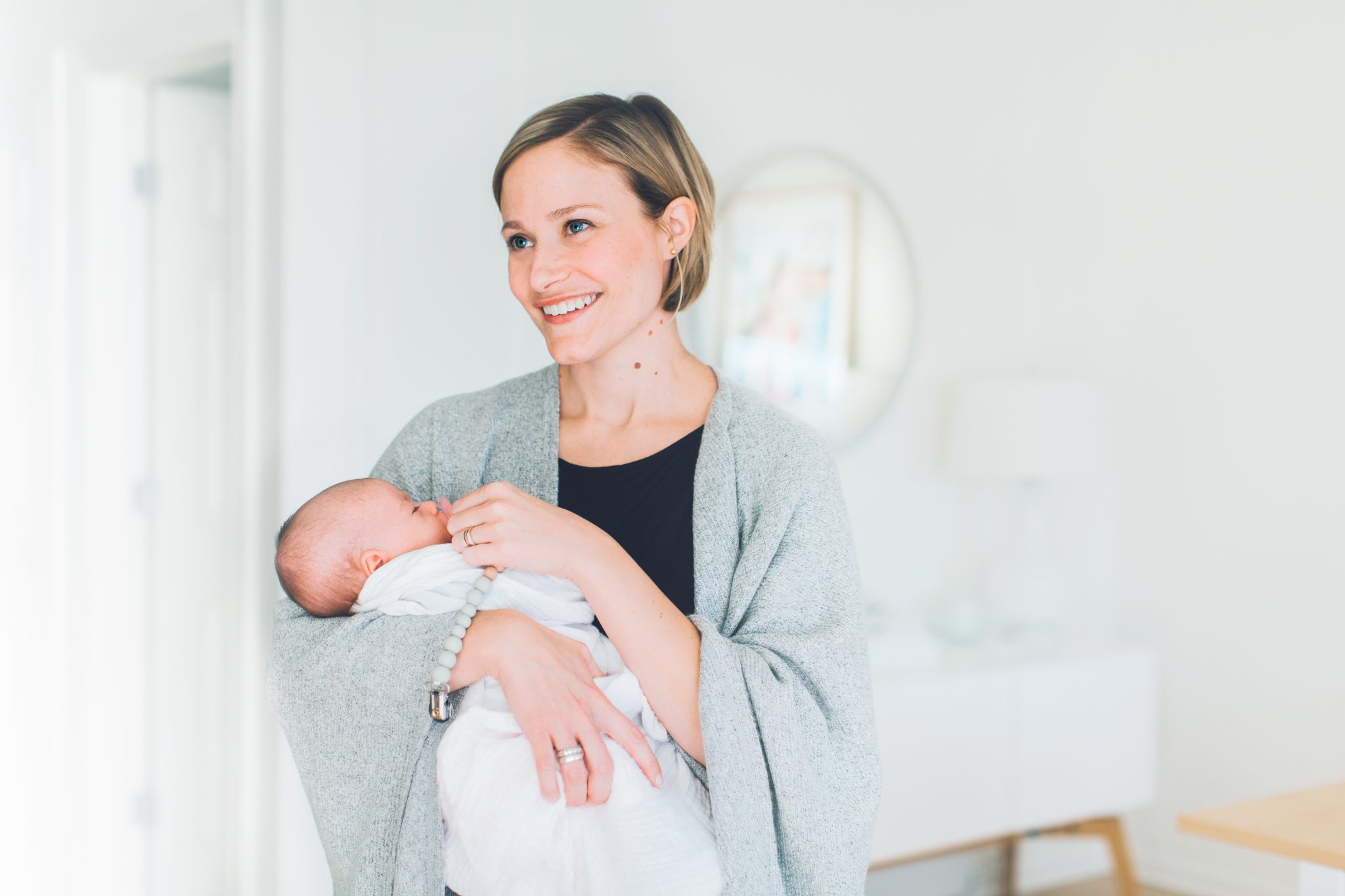 photo of mom holding newborn in a swaddle in home